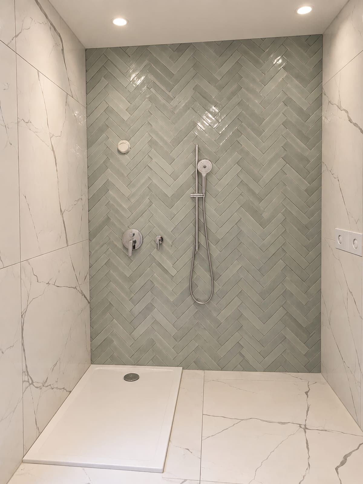 Salle de bain terminée avec zellige vert en chevron et grands carreaux effet marbre blanc